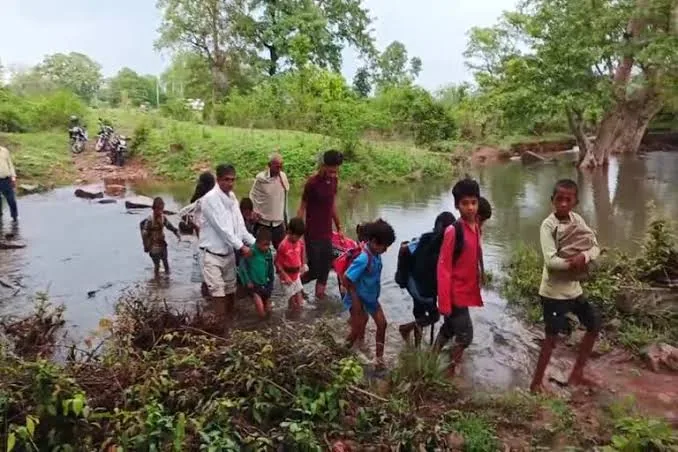 खतरनाक सफर: गोरखपुर में बच्चे कच्चे रास्ते से पानी में घुसकर स्कूल पहुंच रहे हैं